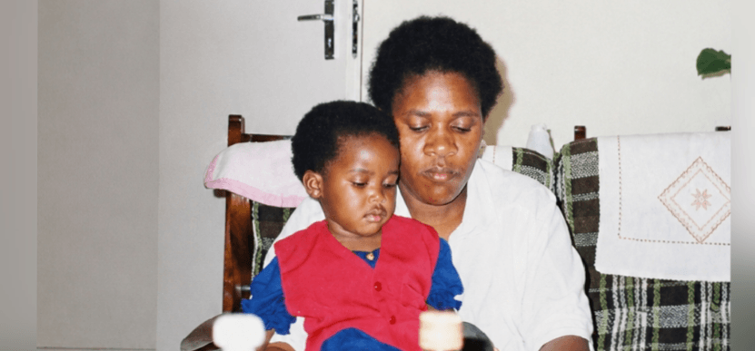 A young Tonia sitting on mom's lap, focusing on mom putting on her shoes.