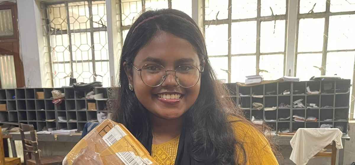 A young Bangladeshi woman smiling while holding a package she received as a winner of an international event.