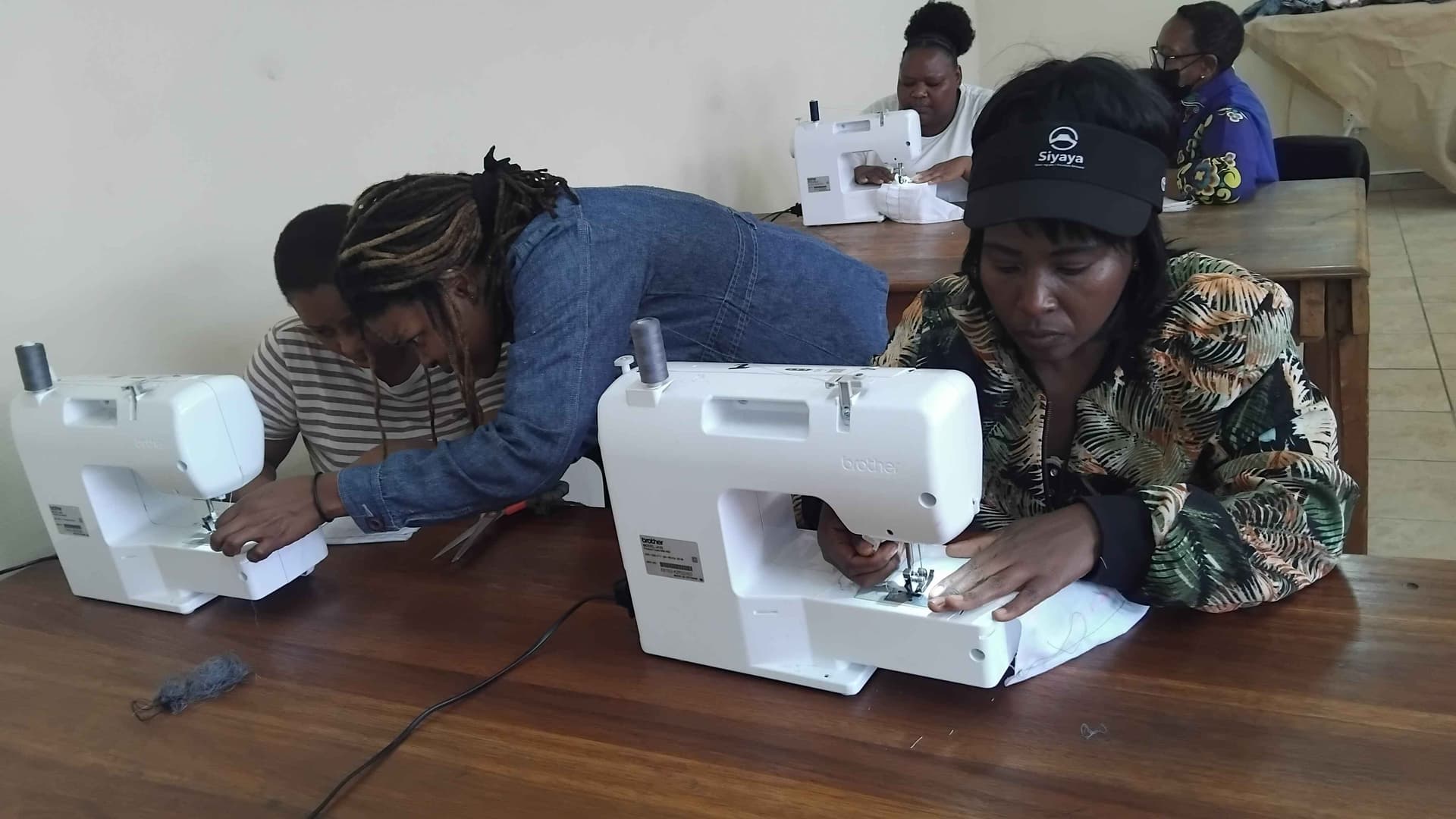 Group of women learning sewing together, sharing stories and helping each other. Not only sewing training but also strengthening community.